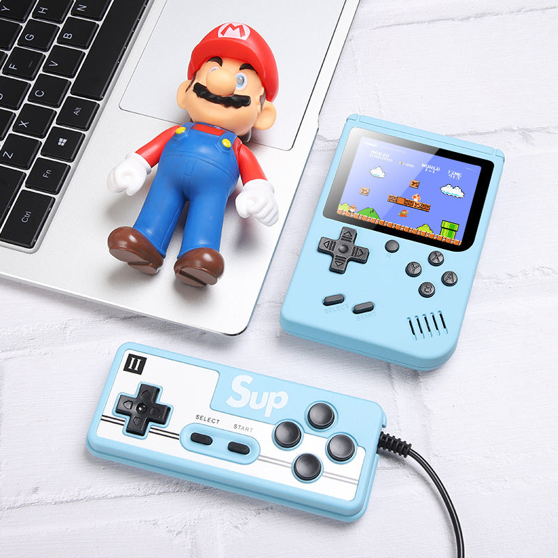 Handheld game console with controller and Mario figurine on a light surface