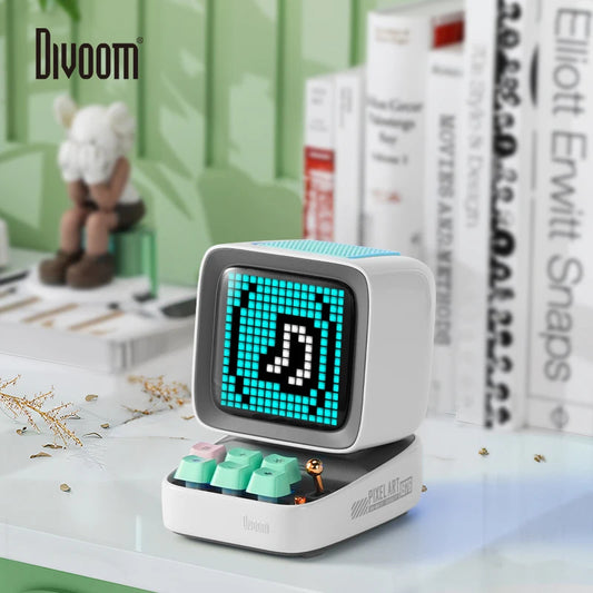 Small electronic device with a digital display on a desk, featuring the brand 'Divoom'.